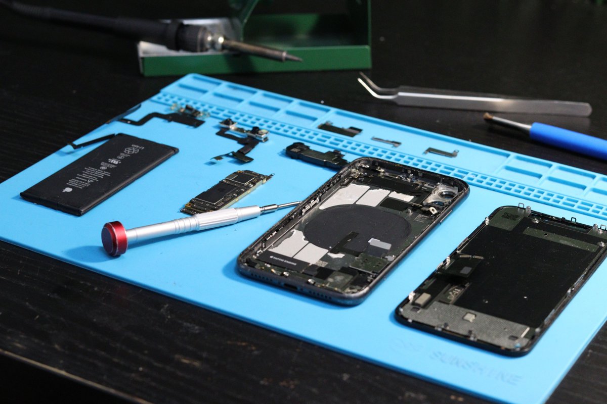 Celular desmontado com bateria e tela separadas na bancada