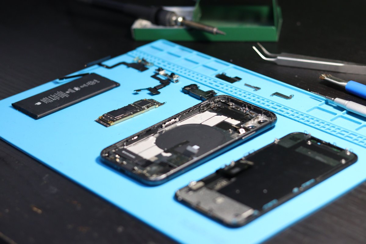 Celular desmontado e componentes internos em uma bancada de reparos